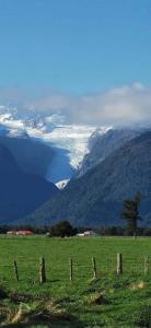 un champ avec une clôture en face d'une montagne enneigée dans l'établissement Glacier View Motel - Franz Josef, à Franz Josef
