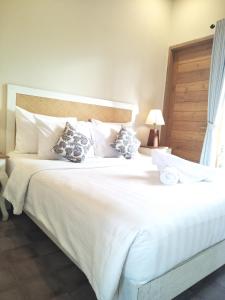 een groot bed met witte lakens en kussens bij Jukung Guest House in Sanur
