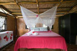 um quarto com uma cama rosa e um urso de peluche em Busuanga Backpackers em Concepcion