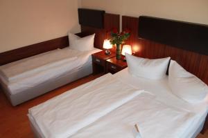 2 camas en una habitación de hotel con sábanas blancas en City Hotel Mercator en Frankfurt