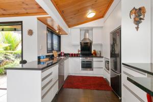 a kitchen with white cabinets and a red rug at Sandy Toes Holiday Home Orewa in Orewa