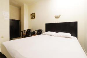 a white bed with two white pillows on top of it at Hotel Gani in Jakarta