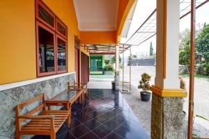 une terrasse couverte d'un bâtiment avec une table et des bancs dans l'établissement Hotel BIP Tawangmangu, à Solo