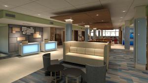 een lobby met 2 monitors en tafels en stoelen bij Holiday Inn Express & Suites - Bensenville - O'Hare, an IHG Hotel in Bensenville