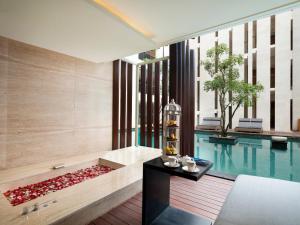 a bathroom with a tub next to a swimming pool at Grand Seminyak - Lifestyle Boutique Bali Resort in Seminyak