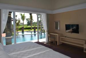 a bedroom with a bed and a view of a pool at Kori Maharani Villas & Resort in Keramas