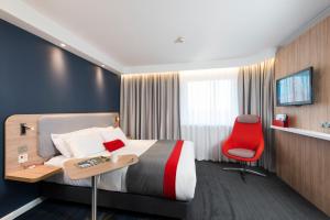 a hotel room with a bed and a red chair at Holiday Inn Express Edinburgh - Leith Waterfront by IHG in Edinburgh
