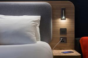 a bed in a hotel room with a white pillow at Holiday Inn Express Edinburgh - Leith Waterfront by IHG in Edinburgh