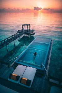 a person in a swimming pool on a dock in the water at Angsana Velavaru In-Ocean Villas - All Inclusive SELECT - Limited time offer Book 3 Nights and get 2 additional Nights Complimentary extension stay in Beachfront Villa with Half Board Meal Plan in Dhaalu Atoll