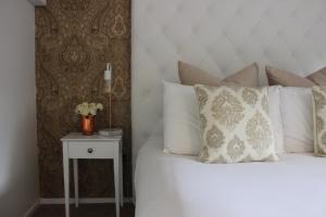 a bed with white pillows and a side table at Orewa Beachcomber in Orewa