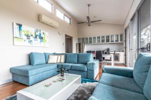 una sala de estar con sofás azules y una mesa. en Adina Vineyard, en Lovedale
