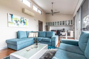 a living room with blue couches and a table at Adina Vineyard in Lovedale