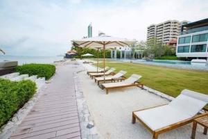 una fila de sillas y una sombrilla junto a una piscina en Veranda Residence Pattaya 112, en Na Jomtien