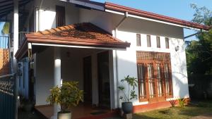 a white house with a gate and a porch at Hotel Red Rose in Negombo