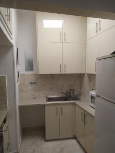 uma cozinha com armários brancos e um lavatório em Michali's Koukaki Apartment (metro Sygrou/Fix) em Atenas