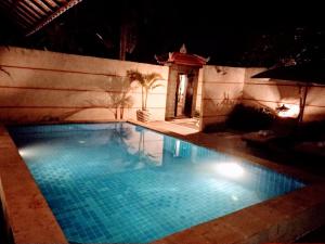 Kartika Dahayu Private Pool Villas في سوكاواتي: حمام سباحة في الليل مع تشغيل الأضواء