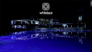 a lit up pool in front of a building at night at WhiteLace Resort in Jbeil