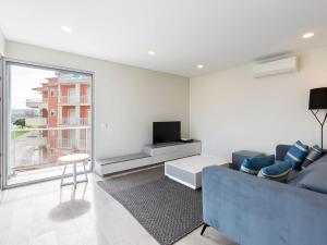 a living room with a blue couch and a tv at Beautiful Apartment in S o Martinho do Porto with Balcony in São Martinho do Porto