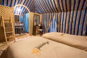 a bedroom with two beds in a room with blue stripes at Azawad Luxury Desert Camp in Merzouga