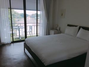 a bedroom with a bed with a view of a balcony at Baan Khun Nine in Ratchaburi