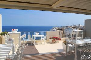 einen Balkon mit Tischen, Stühlen und Meerblick in der Unterkunft Malù Bed&Breakfast in Polignano a Mare