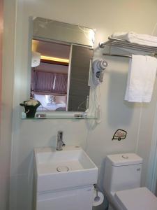 a bathroom with a sink and a toilet and a mirror at Ouxiang Manor Hotel in Yuanlin