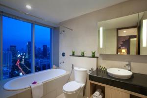 
a bathroom with a tub, toilet and sink at Citadines Rasuna Jakarta in Jakarta
