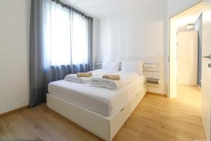 un letto bianco in una stanza con una grande finestra di Apartment Terme a Merano