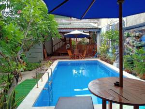 a swimming pool with a table and an umbrella at The Mel Homestay in Nusa Penida