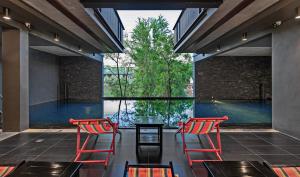 twee rode stoelen en een tafel voor een zwembad bij Hua Hin Habitat Hotel- SHA Extra Plus in Hua Hin