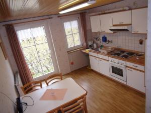 eine Küche mit weißen Schränken, einem Tisch und 2 Fenstern in der Unterkunft Feriengut Dietzsch in Pöritzsch
