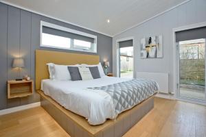 a bedroom with a large bed and two windows at Nyland Lodge, Strawberryfield Park in Cheddar