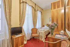 a room with a bed and a tv and a table at Hotel Sirius in Karlovy Vary