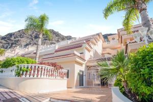 dom z palmami przed górą w obiekcie Vivienda Vacacional Los Gigantes w mieście Santiago del Teide
