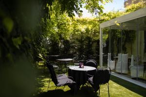 un patio con mesas y sillas en un jardín en Hotel Cavallino Bianco, en Cavallino-Treporti