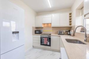 a kitchen with white cabinets and a sink at 2 BED Modern apartment. Close to station & PARKING in Slough