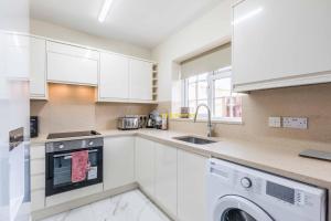 a kitchen with white cabinets and a washer and dryer at 2 BED Modern apartment. Close to station & PARKING in Slough