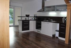a kitchen with black and white appliances and wooden floors at Private holiday house Vivendi in Liptovský Mikuláš