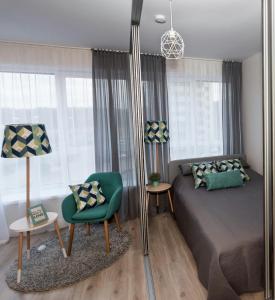 a bedroom with a bed and a green chair at Relax apartments near Egle in Druskininkai