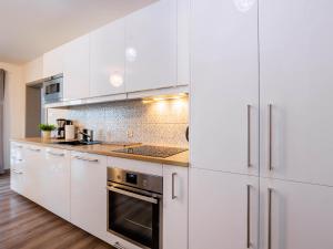 a white kitchen with white cabinets and a stove at VacationClub – 5 Mórz Sianożęty Apartament 1i/13 in Sianozety