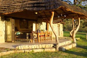 a patio with a hut with a table and chairs at Franshoek Farm in Ficksburg