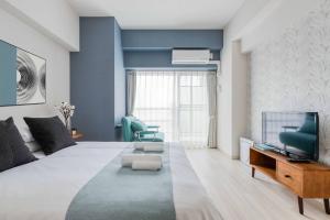 a living room with a large bed and a tv at Ostay Shin-Osaka Hotel Apartment in Osaka