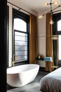 La salle de bains est pourvue d'une baignoire blanche devant une fenêtre. dans l'établissement Stella Suites Boutique Hotel, à Goirle