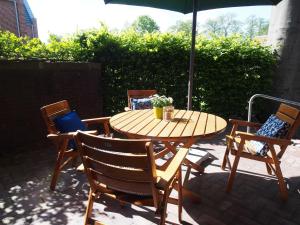 einen Holztisch und Stühle mit Sonnenschirm auf einer Terrasse in der Unterkunft Ferienwohnung Alte Fehnapotheke, 95144 in Rhauderfehn