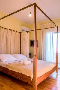 um quarto com uma cama de dossel em madeira com lençóis brancos em Villa Marata em Kokkíni Khánion