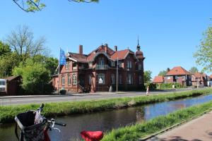 a house on the side of a river with a bike at Ferienwohnung Alte Fehnapotheke, 95144 in Rhauderfehn