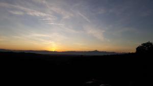 zachód słońca na polu ze słońcem na niebie w obiekcie Agriturismo Cascina Binelli w mieście Dogliani