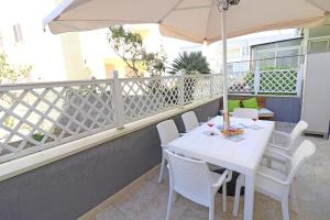 einen weißen Tisch mit Stühlen und einem Sonnenschirm auf dem Balkon in der Unterkunft Holiday Apartment With Wi-fi, Air Conditioning And Balcony; Pets Allowed in Otranto