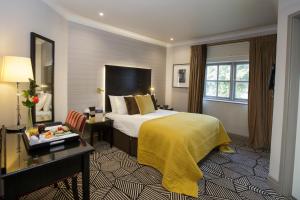 ein Hotelzimmer mit einem Bett, einem Schreibtisch und einem Spiegel in der Unterkunft Hunton Park Hotel in Kings Langley
