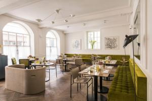 un restaurante con mesas y sillas y un sofá verde en Hôtel de Tourrel, Saint Rémy de Provence, a Member of Design Hotels en Saint-Rémy-de-Provence